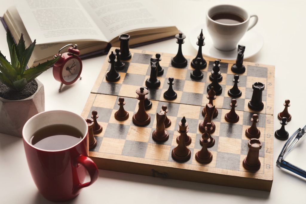 Wooden desk with chess play, book and coffee cup
