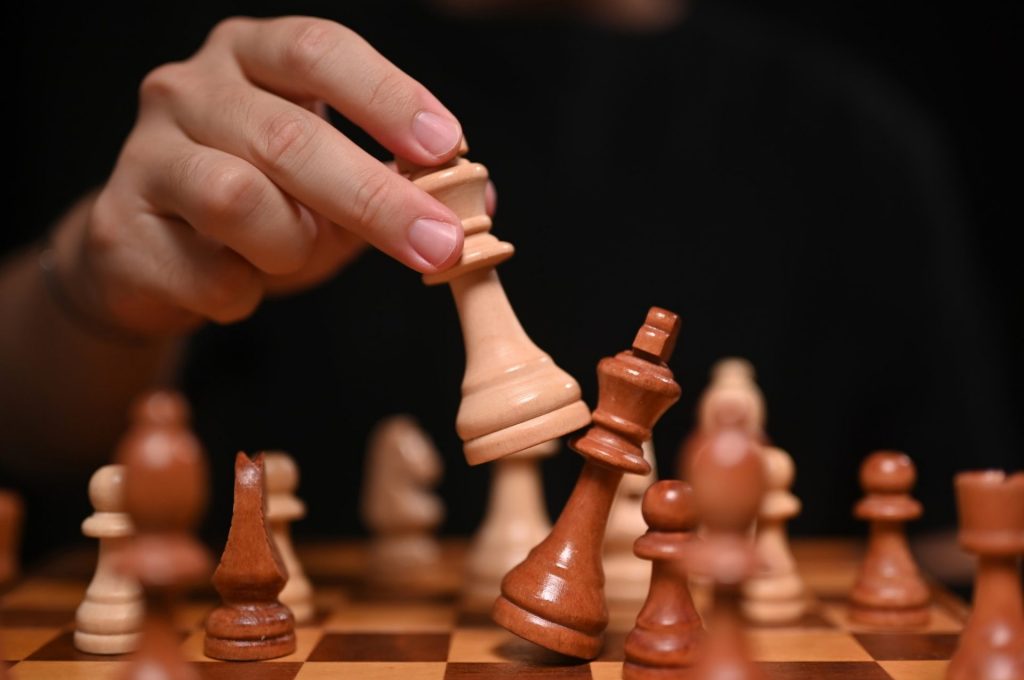 Businessman moving chess piece and checkmate during competition.