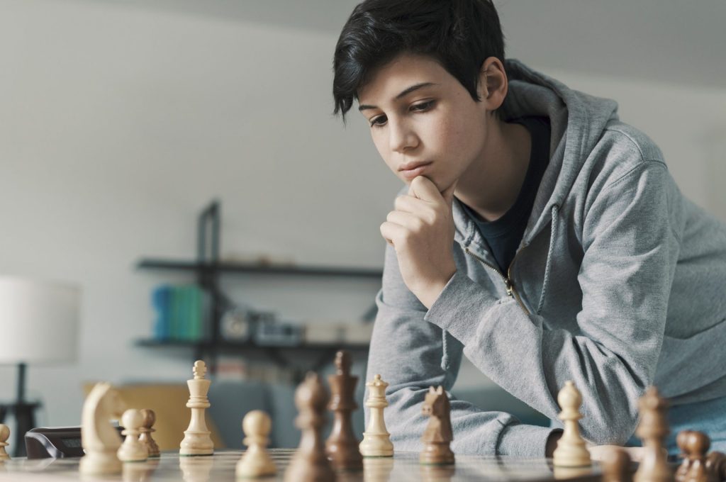 Smart boy playing chess and staring at the chessboard