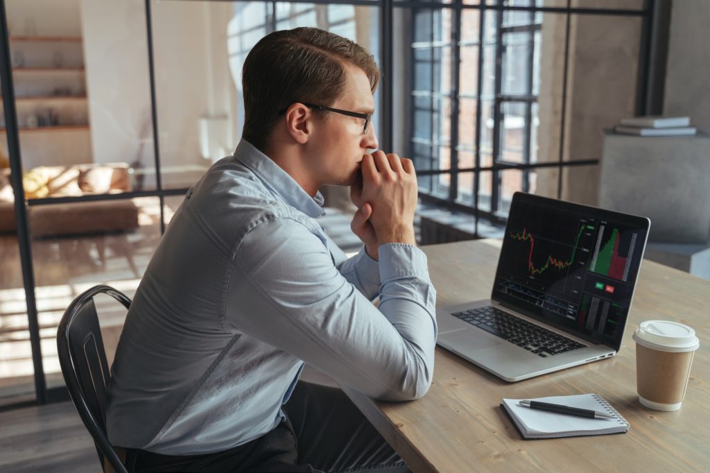 Crypto trader checking candlestick chart worried about global risks, recession and financial crisis