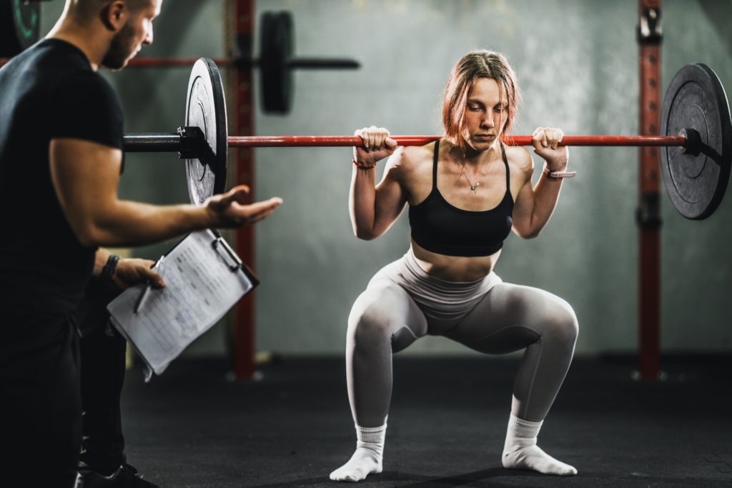 Woman Exercising With Personal Trainer At The Gym