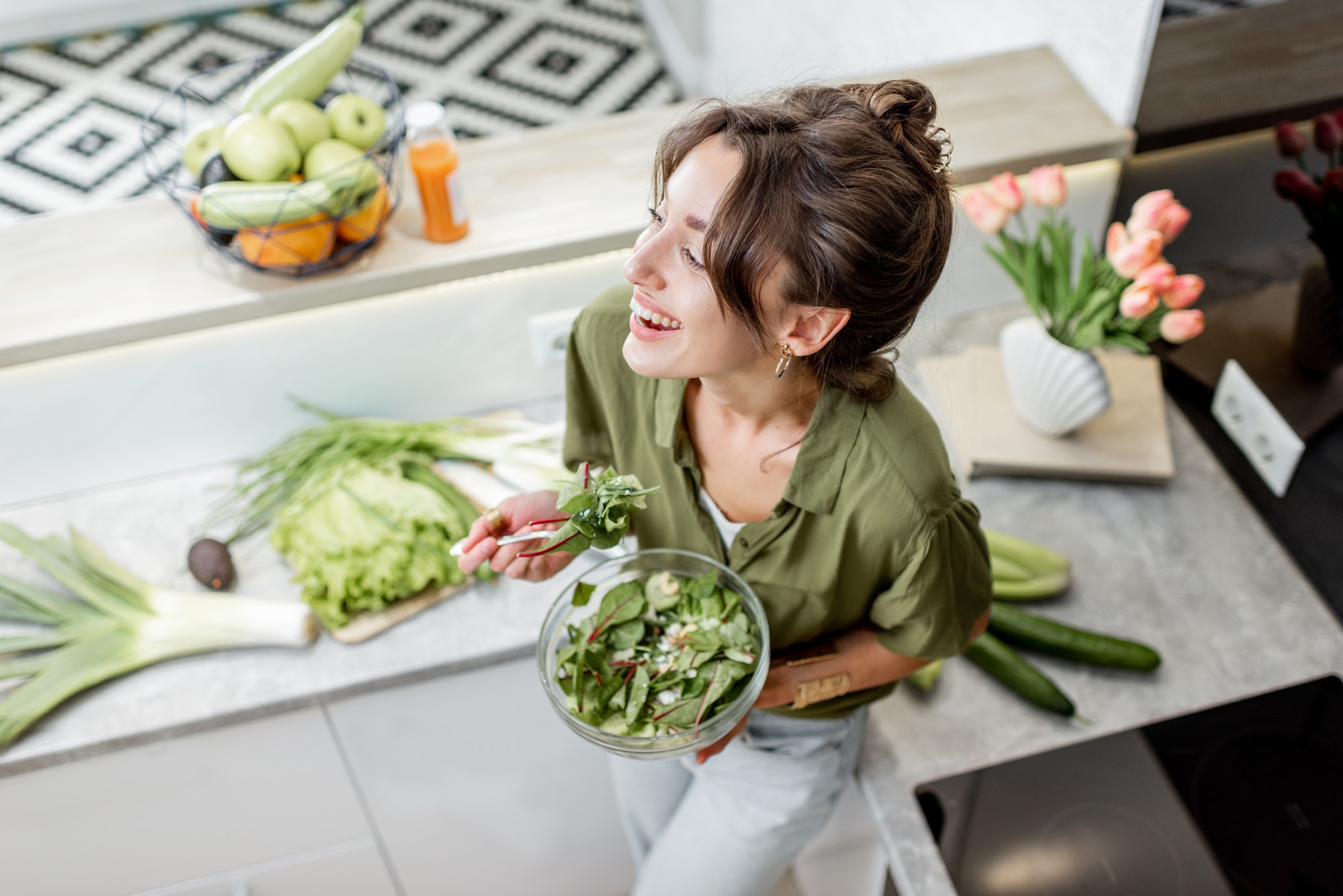 Woman eating salad on the kitchen at home