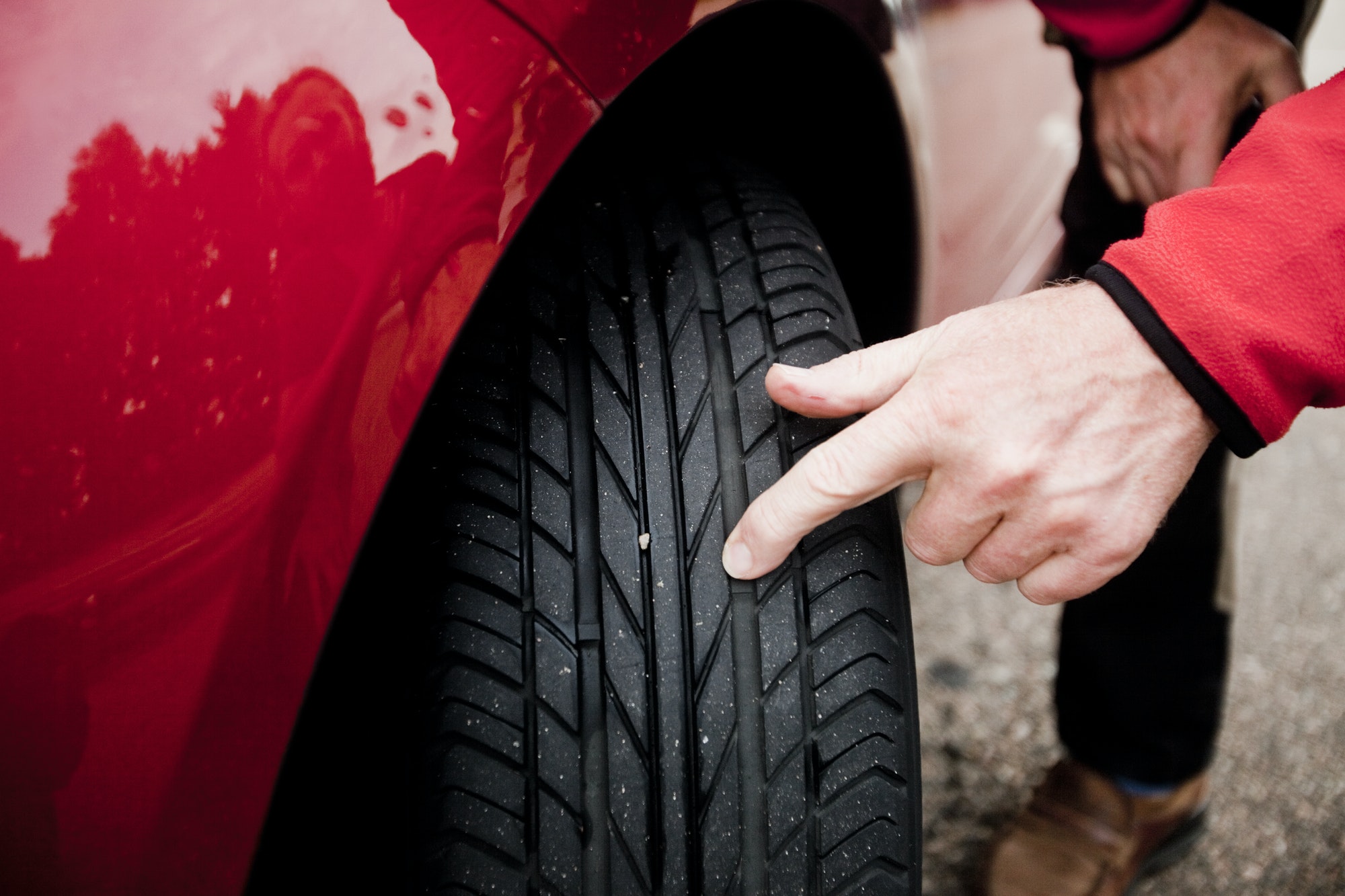Cropped image of man examining car tire