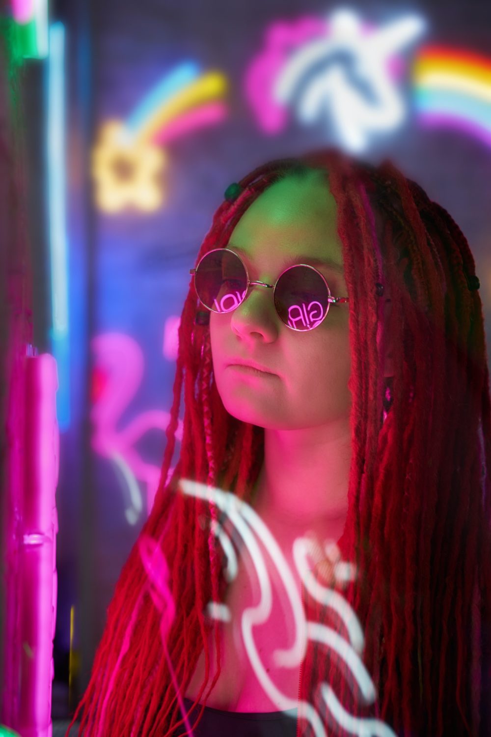 Girl in neon lights, beautiful woman in sunglasses, with pink hair, with dreadlocks pigtails