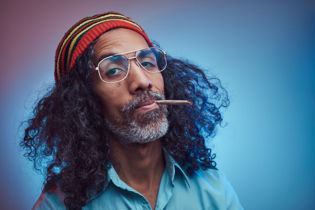 Studio portrait of African Rastafarian male smoking cigarettes