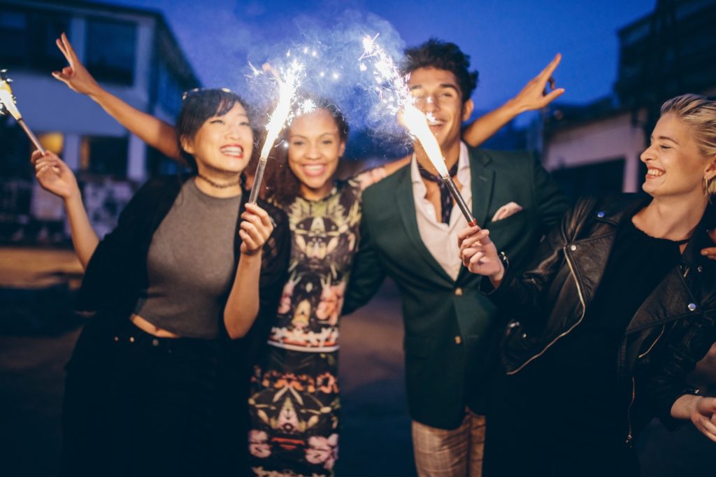 Young friends having night party with sparklers