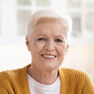 Portrait of cheerful old woman sitting in kitchen