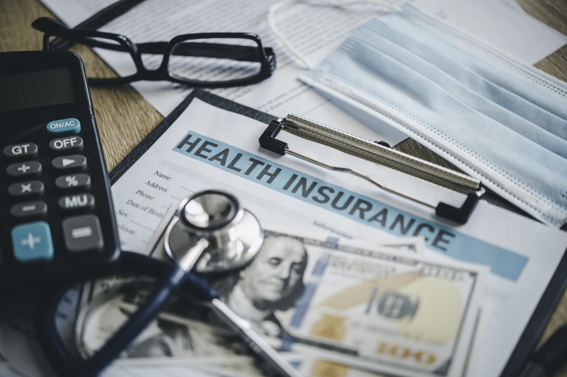 Stethoscope and calculator placed on health insurance documents,