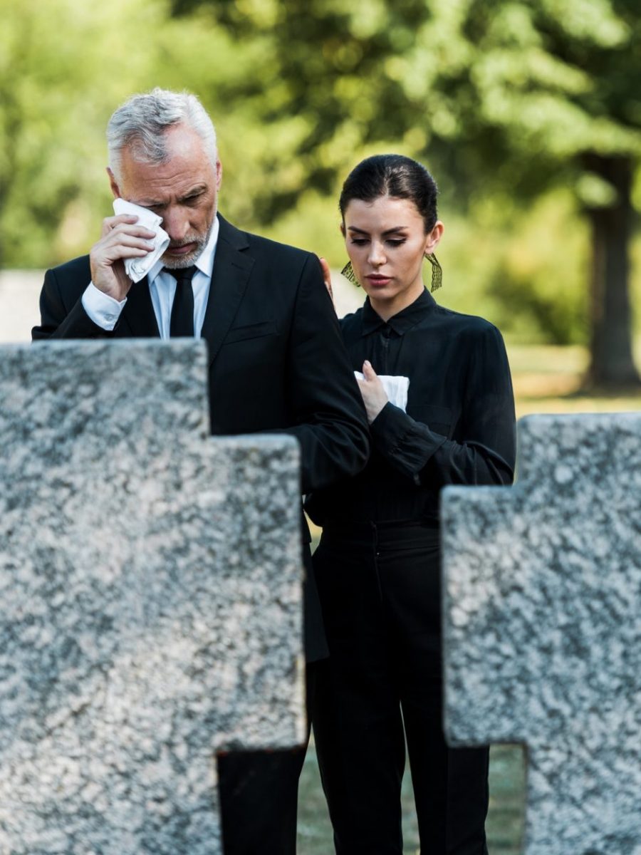 selective focus of upset man crying near woman on funeral