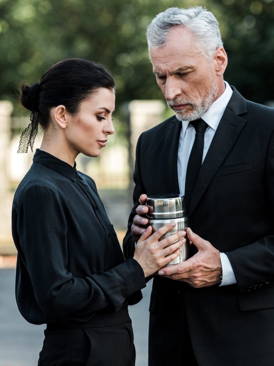 senior man and attractive woman holding mortuary urn