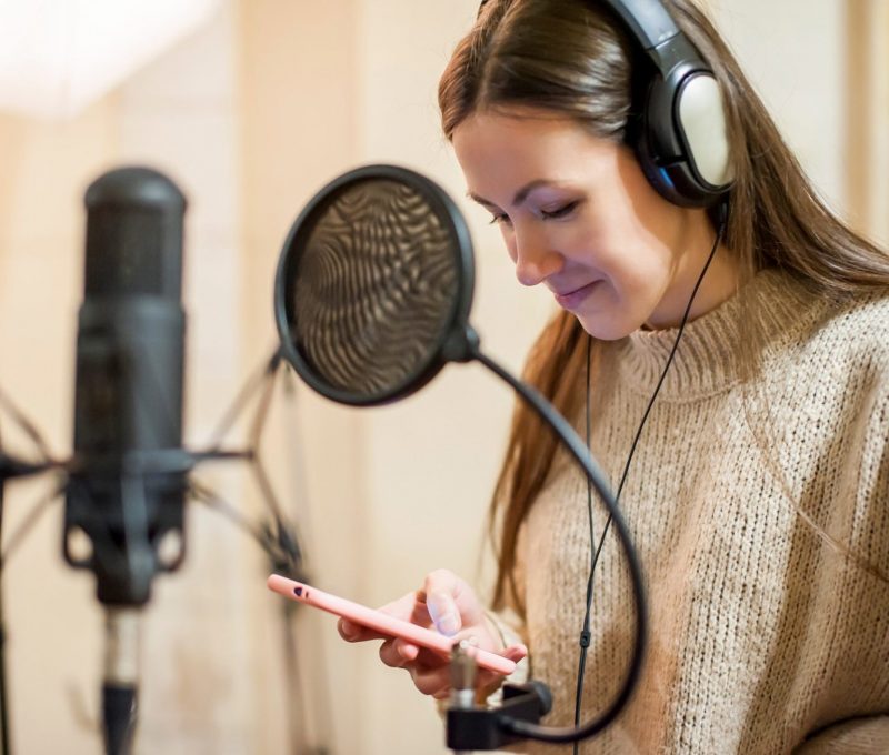 Young girl singer recording vocals in professional recording studio close-up