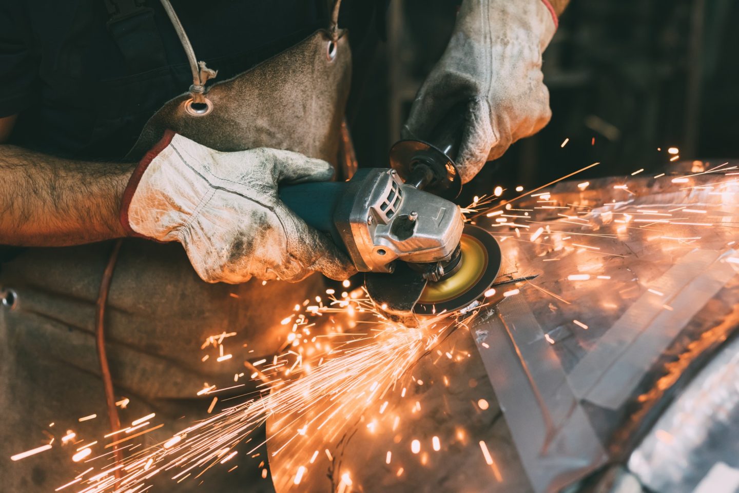 Hands of metalworker grinding copper in forge workshop