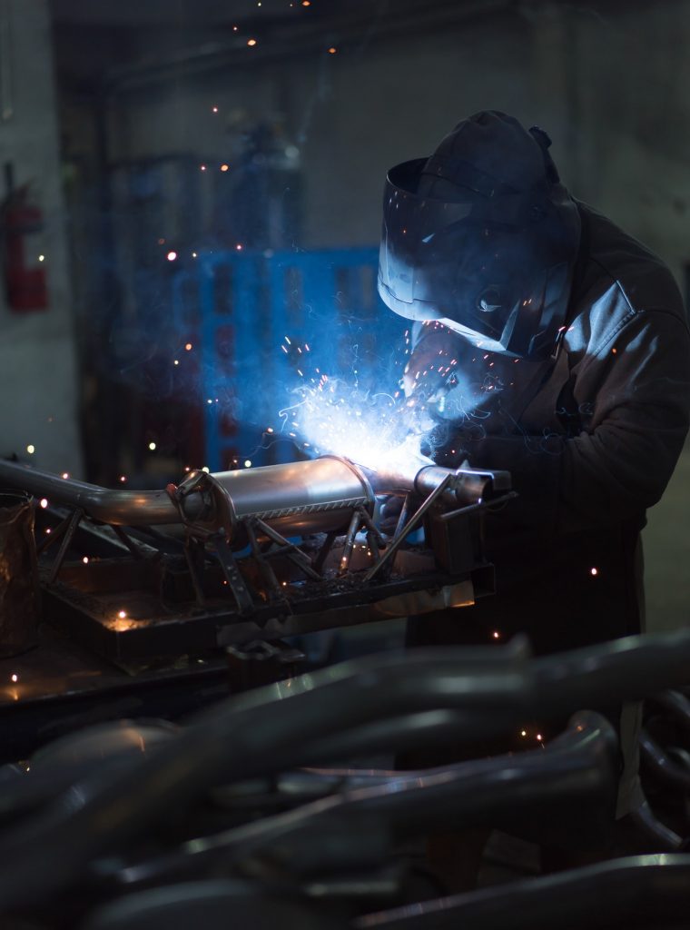 worker welding exhaust pipes pieces together