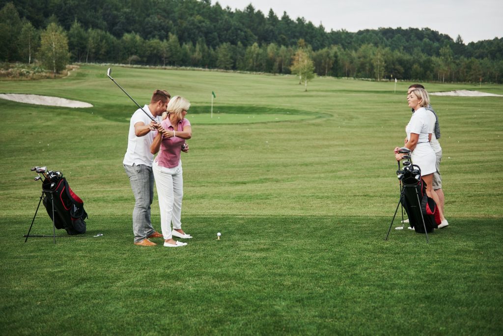 Girl playing golf and hitting by putter on green