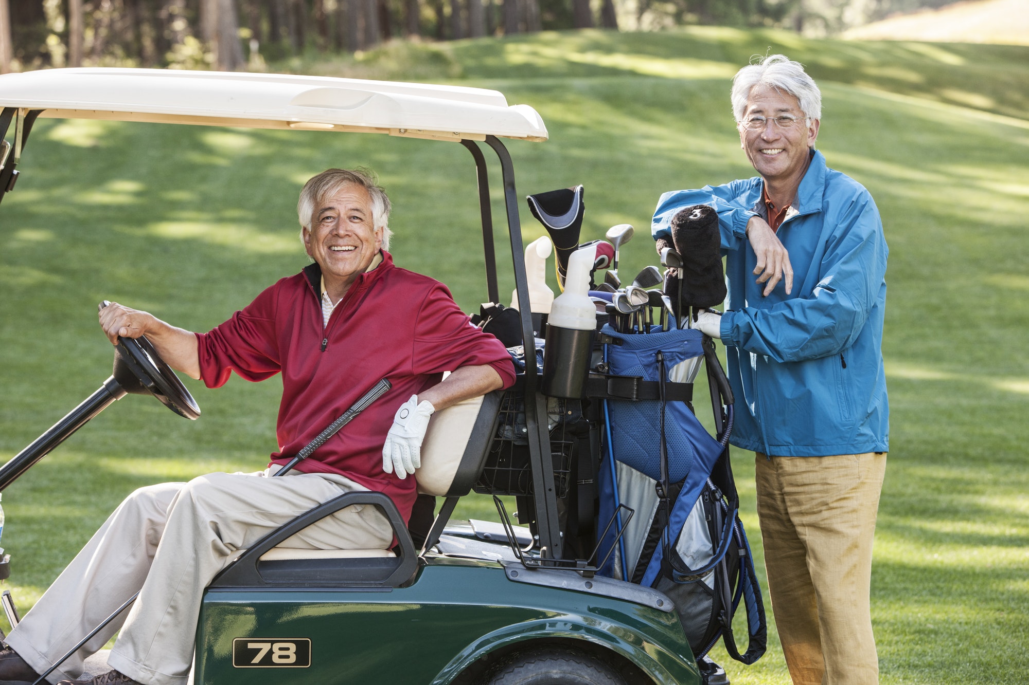 Two senior male golfing buddies and their golf cart and clubs.