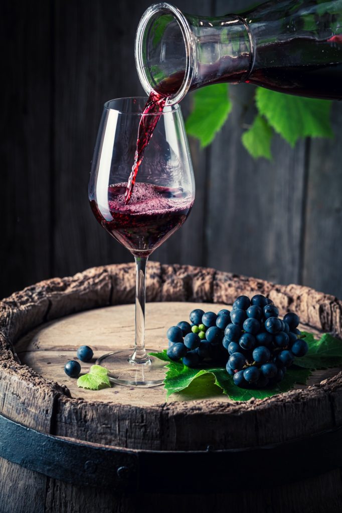 Pouring red wine from carafe into a glass. Wine industry.