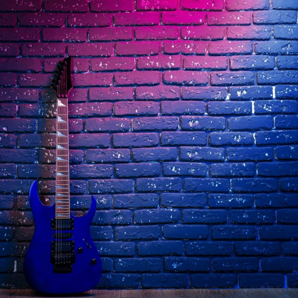 Electric guitar in neon light against dark walll