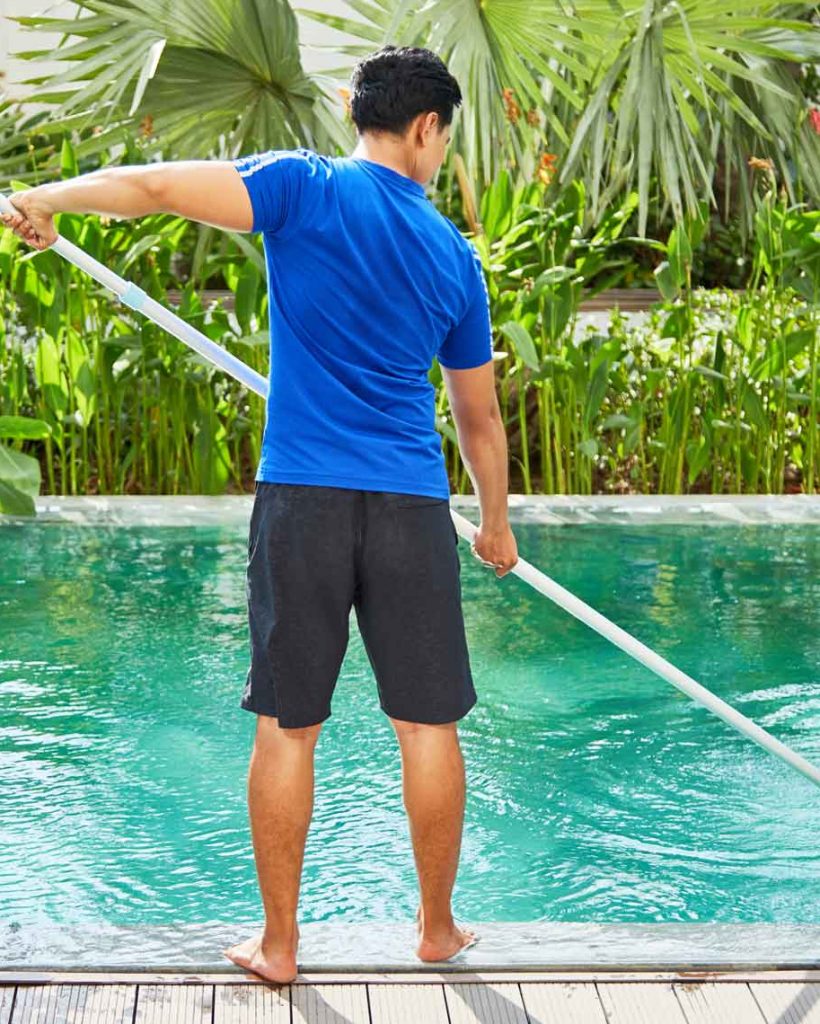 Young man cleaning pool
