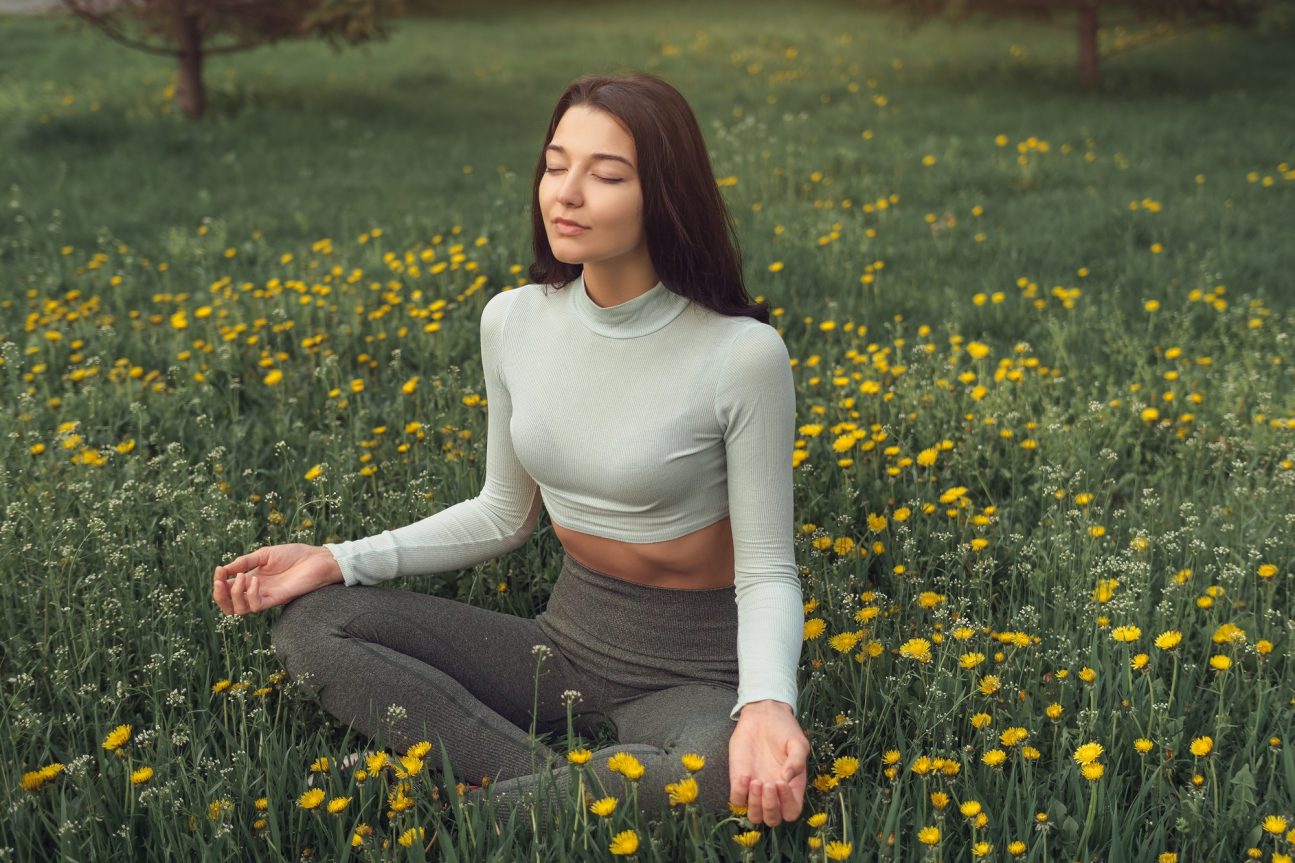 Woman Meditating on the Meadow Outdoors