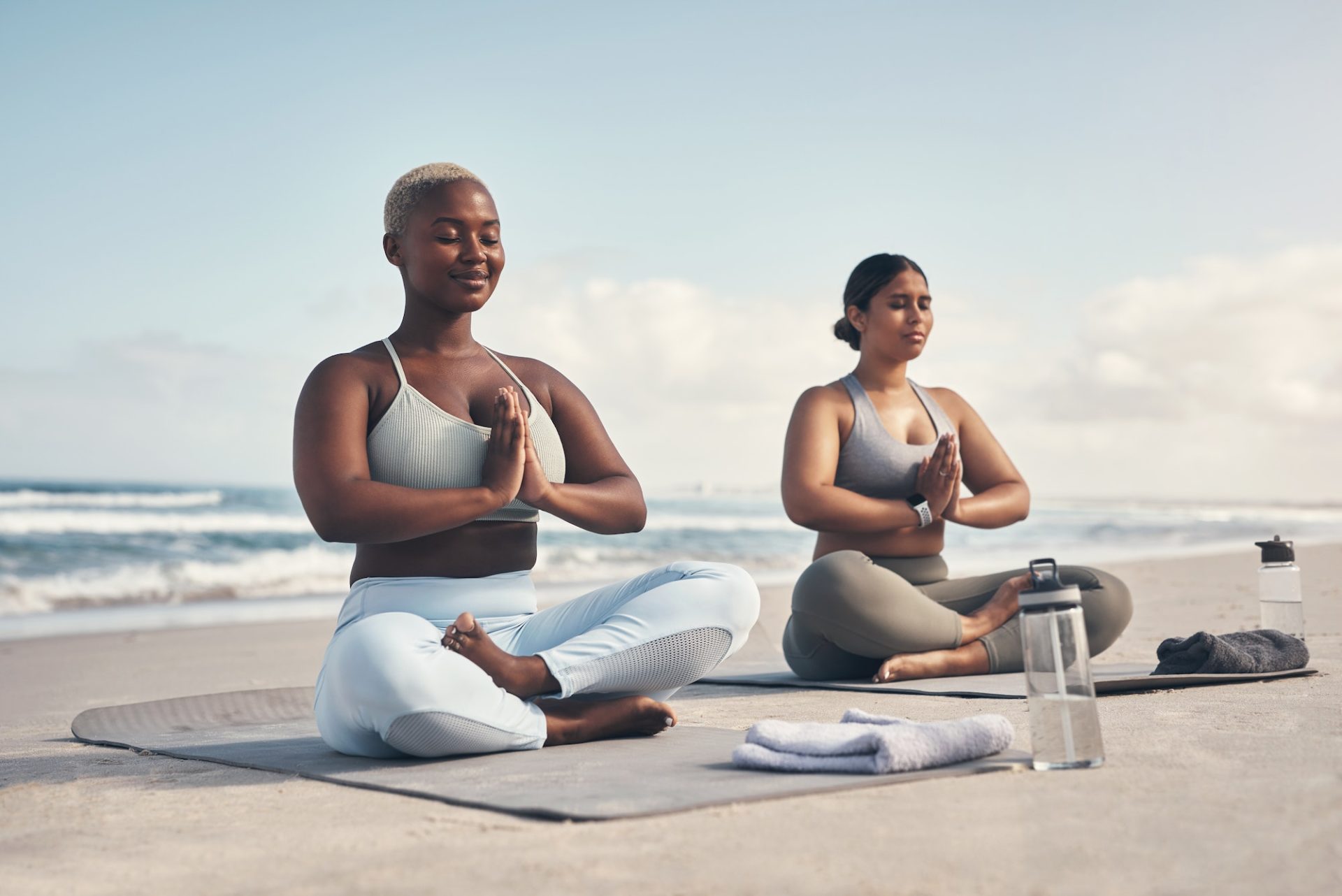 Shot of two young women meditating during their yoga routine on the beach