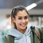 Young happy woman at refrigerated section of supermarket looking at camera.